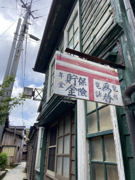 貯金・保険・年金の看板が残る宿根木の古い郵便局建築、レトロな町並み