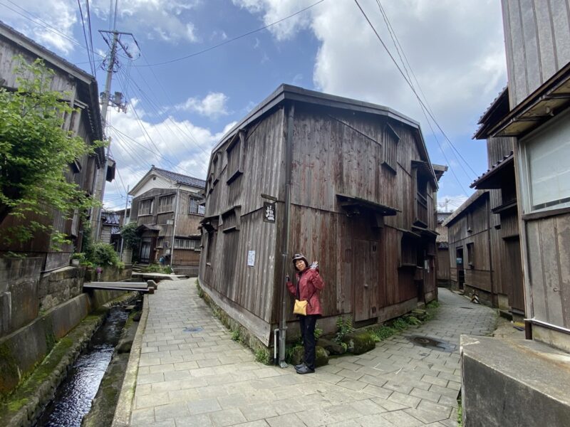 宿根木の象徴である三角家を正面から望む路地と水路、伝統的建造物の町並み