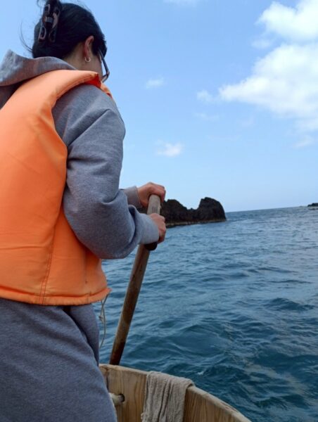 ライフジャケット姿でたらい舟を漕ぐ体験、青空と岩礁の矢島経島