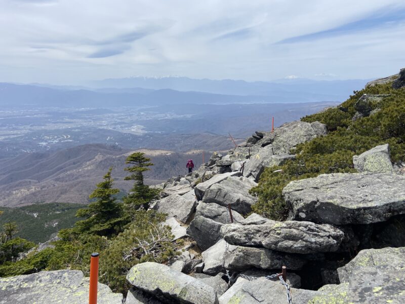蓼科山の岩場から見下ろす茅野の街並みと残雪の南アルプス