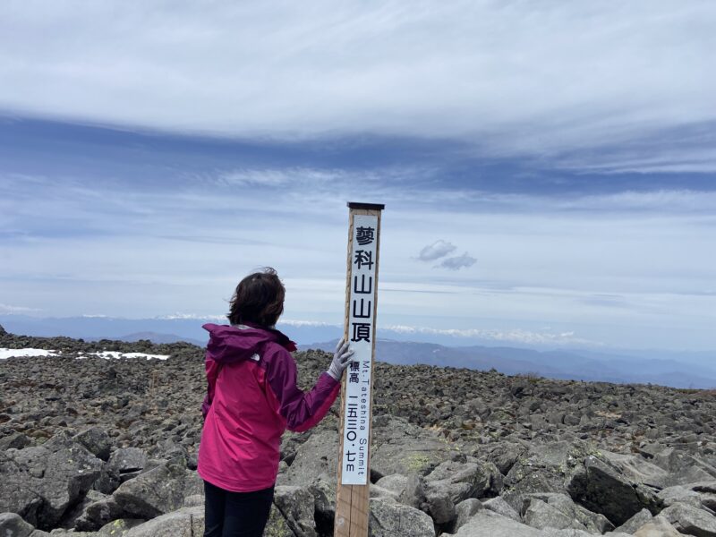 蓼科山の山頂標を背に立つ残雪期の春山登山